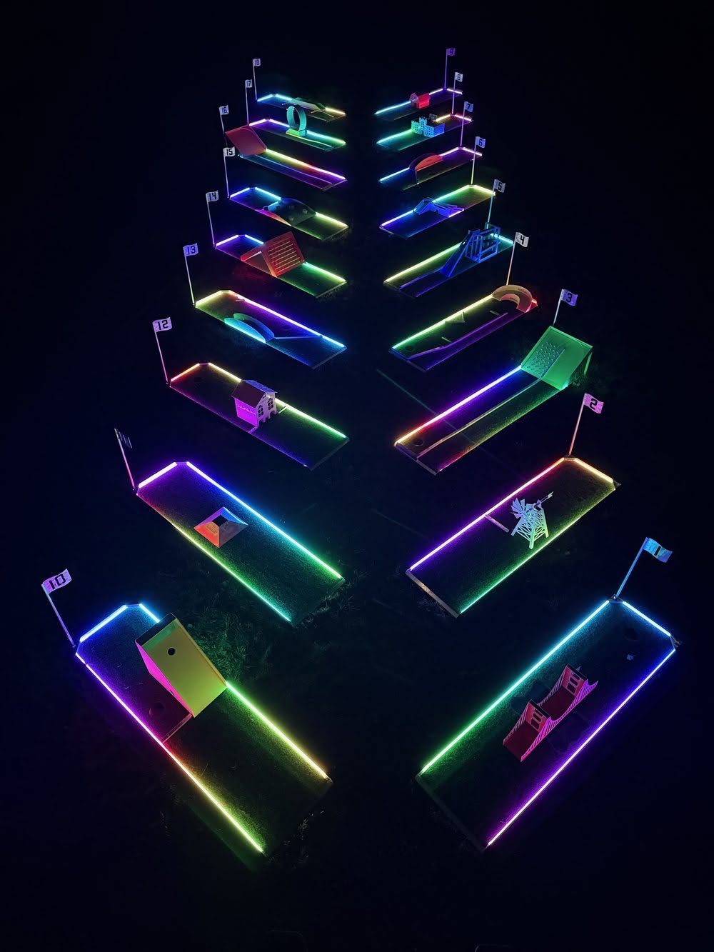 Aerial view of LED-lit aluminum mini golf lanes glowing at night
